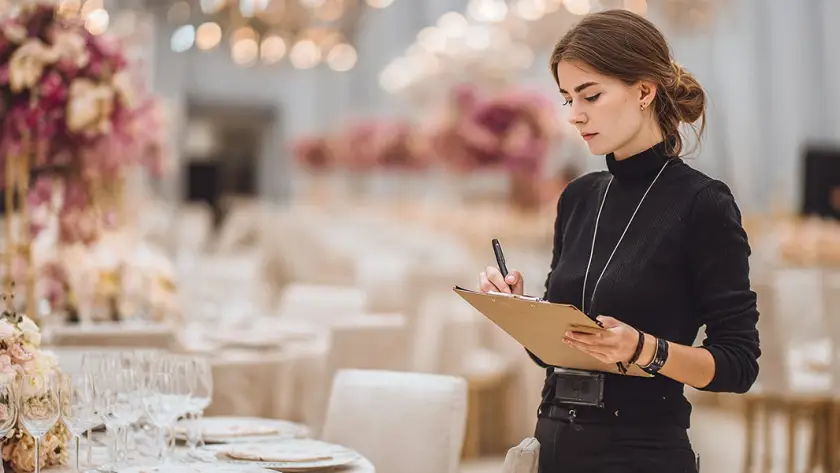 A professional event planner checking a clipboard at a luxury gala, showcasing the services of a top Event Management Company.
