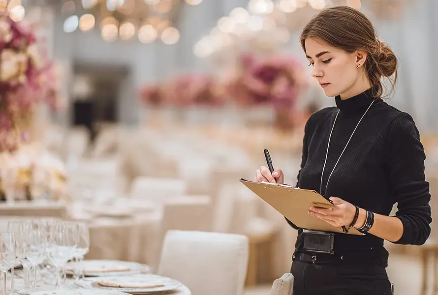 A professional event planner checking a clipboard at a luxury gala, showcasing the services of a top Event Management Company.